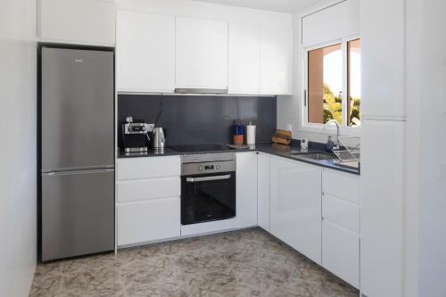 a kitchen with white cabinets and a stainless steel refrigerator at Casa Blanca in El Vendrell