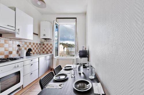 une cuisine avec une table avec des assiettes et des verres dessus dans l'établissement L'Oasis Urbaine - Spacieux et élégant pour 5 pers, à Saint-Fons