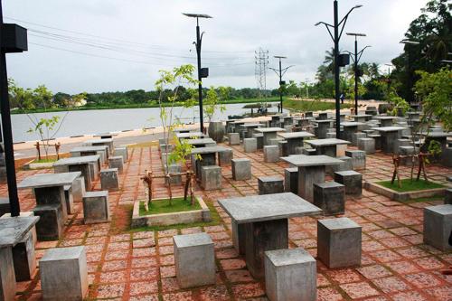 a group of tables and benches in front of a body of water at Amaze Residence luxury 2 bedroom apartment 3 in Boralesgamuwa