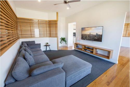 a living room with a couch and a flat screen tv at La Maison Elegante in Kalimna