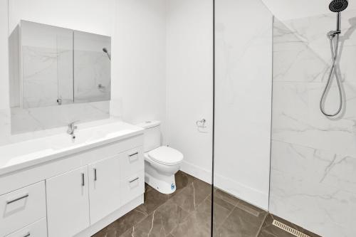 ein weißes Badezimmer mit Toilette und Dusche in der Unterkunft Camellia Cottage on Church in Lakes Entrance