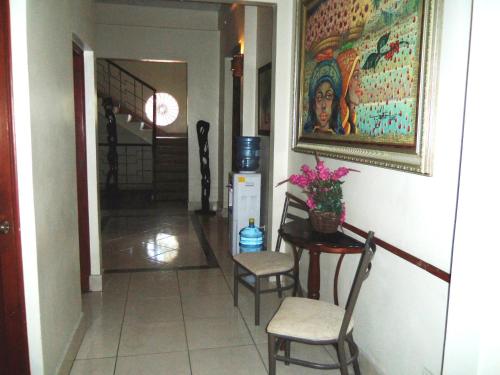 a hallway with a table and chairs and a painting at Hotel Discovery in Santo Domingo