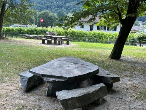 a stone bench and picnic tables in a park at Cà Maria in Bignasco