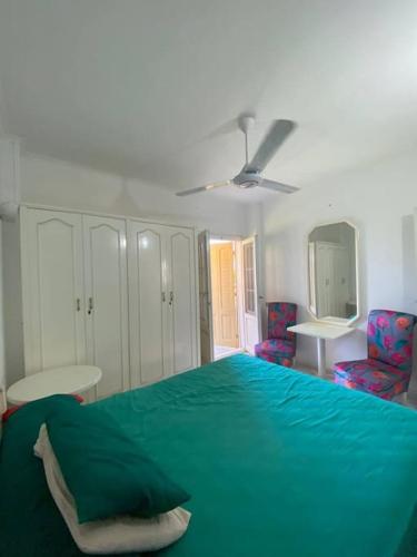 a bedroom with a green bed and two chairs at شاليه بمساحة خضراء رائعة in Dawwār ‘Abd al Qādir Qāsim