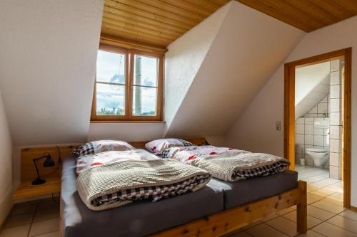 two beds in a attic bedroom with a bathroom at Ferienwohnung in ländlicher Lage in Meckenbeuren