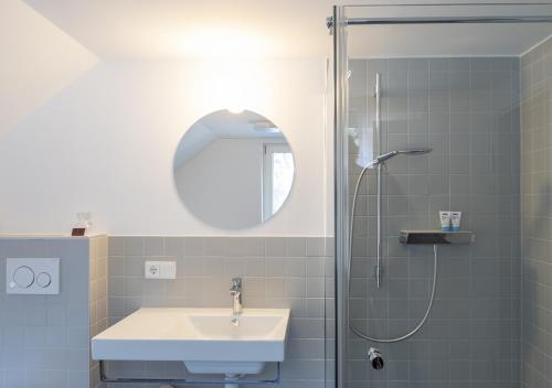 a bathroom with a sink and a shower with a mirror at Gasthof Löwen Tosters in Feldkirch