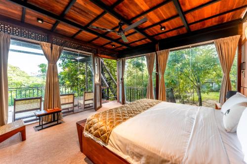 a bedroom with a large bed and large windows at Trance rabara resort in Avissawella