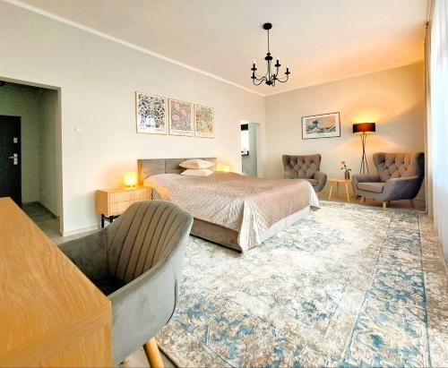 a bedroom with a bed and a couch and chairs at Tullu Apartament - w centrum, blisko bulwaru, blisko molo in Ostróda