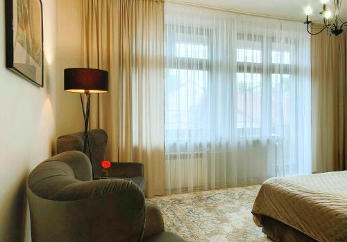 a bedroom with a chair and a bed and a window at Tullu Apartament - w centrum, blisko bulwaru, blisko molo in Ostróda