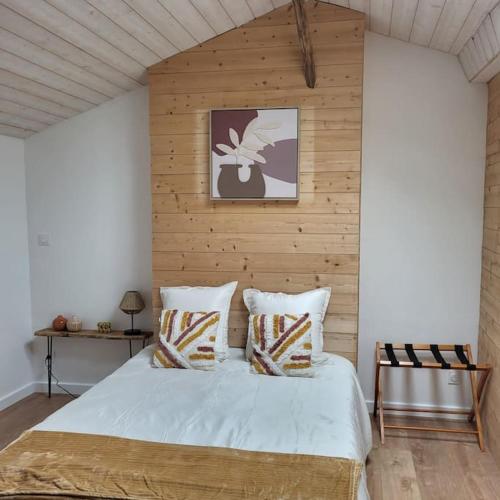 - une chambre avec un lit blanc et un mur en bois dans l'établissement O Nid Naturel, à Mauléon