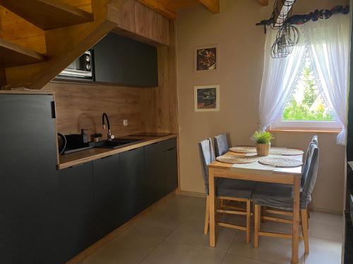 a kitchen with a table with chairs and a sink at Babie Domki in Zawoja