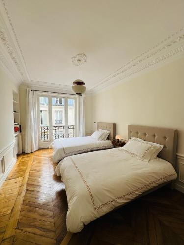 une chambre avec deux lits et une grande fenêtre dans l'établissement 3 bedrooms in Marais, à Paris