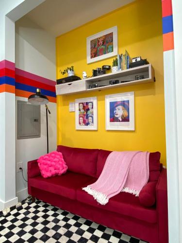 a red couch in a room with a yellow wall at Heart of NY - 17 min to Empire State & Times Sq in Jersey City