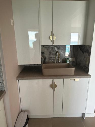 une cuisine avec des armoires blanches et un évier dans l'établissement Splendide vue panoramique sur la Méditerranée, à Cagnes-sur-Mer