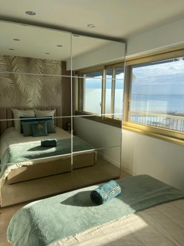 une chambre avec deux lits et une grande fenêtre dans l'établissement Splendide vue panoramique sur la Méditerranée, à Cagnes-sur-Mer