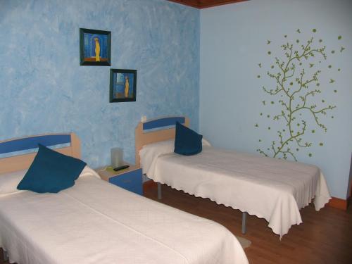 two beds in a room with blue walls at Hotel El Golobar in Reinosa