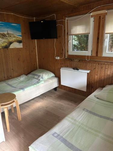 a room with two beds and a tv on the wall at Domki 13-nastka in Międzyzdroje