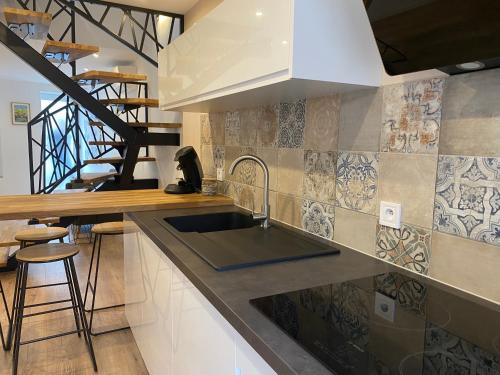 une cuisine avec un évier et un escalier dans l'établissement Maison cosy, à Mauzé-sur-le-Mignon