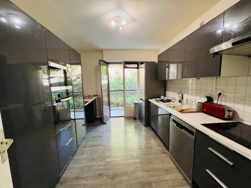 une cuisine avec des armoires noires et des comptoirs blancs dans l'établissement BANDOL ROC BEACH VUE MER Grand T3 face à la plage avec parking, à Bandol