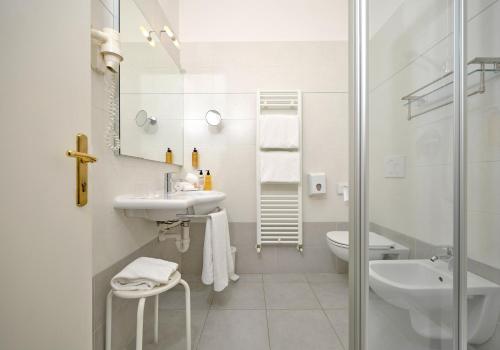 a white bathroom with a sink and a shower at Hotel Eden Garda in Garda