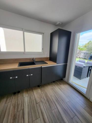 une cuisine avec un évier et une grande fenêtre dans l'établissement maison avec piscine, à Saint-Médard-en-Jalles