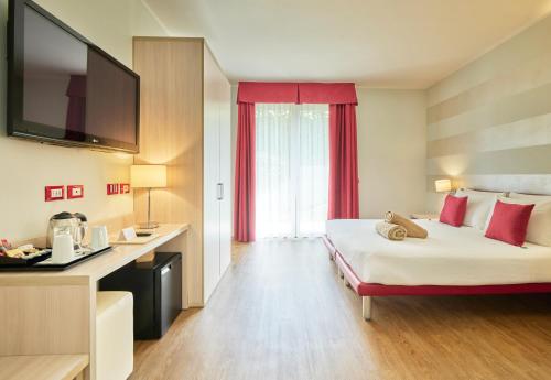 a hotel room with a large bed with red curtains at Hotel Eden Garda in Garda