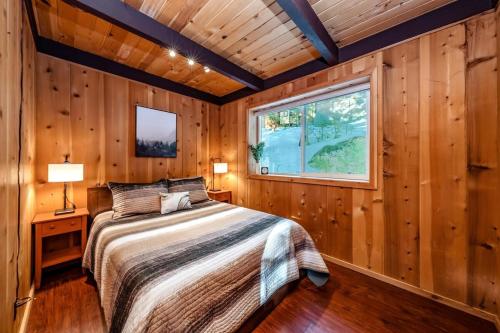 a bedroom with wooden walls and a bed with a window at A-frame Escape Unique Stay W Comfort & Style in Shaver Lake