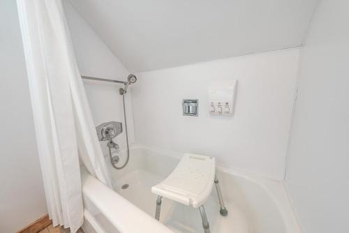a white bathroom with a stool in a bath tub at Buckeye Bear's Den-ac-walking Distance To Town in Shaver Lake