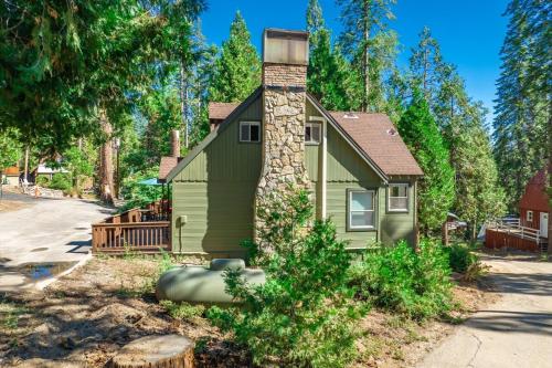 a small green house with a stone chimney at Buckeye Bear's Den-ac-walking Distance To Town in Shaver Lake