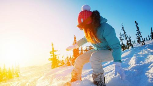 a woman riding a snowboard down a snow covered slope at Buckeye Bear's Den-ac-walking Distance To Town in Shaver Lake