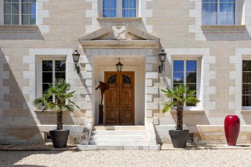 a building with a wooden door and two palm trees at Chateau de Bellevue B&B et Appartements avec Piscine saisonal chauffée et Chambres partout climatisées in Saint-Avit