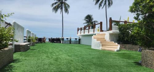 a house with a grass yard with stairs and palm trees at The Rock Samui Beachfront Villas - Sha Plus Hotel in Lamai