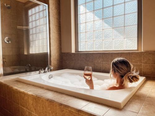 Eine Frau, die in einer Badewanne mit einem Glas Wein sitzt. in der Unterkunft Sierra Pines Villa Deck Jetted Tub Game Rm in Shaver Lake