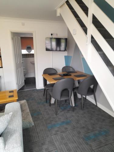 a dining room with a table and chairs and a staircase at clifftop villa 47 in Corton