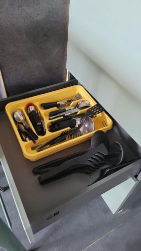 - un plateau jaune avec des ustensiles de cuisine sur une étagère dans l'établissement Studio mer escatade, à Saint-Jean-de-Monts