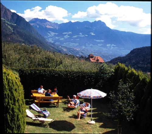 a group of people sitting in chairs under an umbrella at Pföstlhof in Parcines