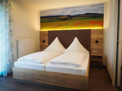 a bedroom with a bed with a painting on the wall at Landgasthof Zum Stern in Hammelburg- Obererthal