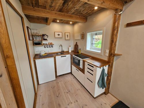 a kitchen with white appliances and a wooden floor at Sigurd's Tiny House in Vossevangen