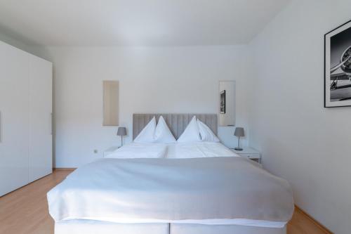 a white bedroom with a large white bed with pillows at FarawayHomes Studio Leoben #A6 in Leitendorf