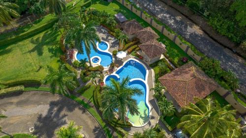an overhead view of a resort swimming pool with palm trees at Villa Encantada By Vacation Pura Vida in Esterillos