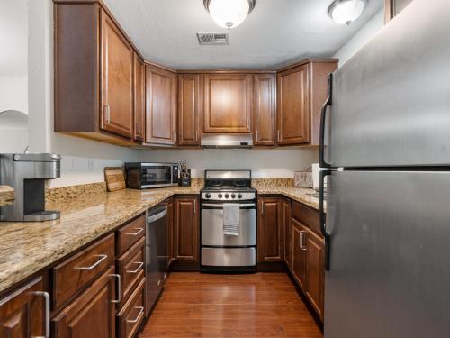 a kitchen with wooden cabinets and a stainless steel refrigerator at Top-notch 2br Spacious Condo With Shared Pool in Scottsdale
