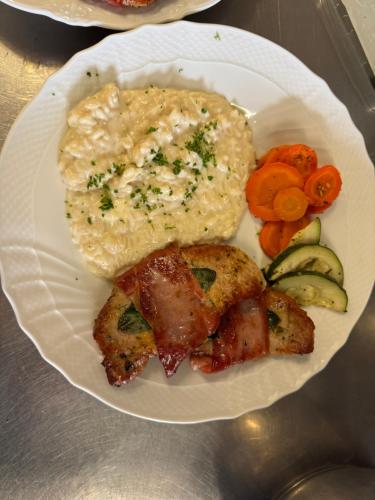 a plate of food with meat and gravy and vegetables at Ustreia Orta in Lohn