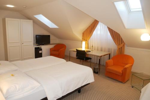 a hotel room with two beds and two chairs at Hotel Schwanen Wil in Wil