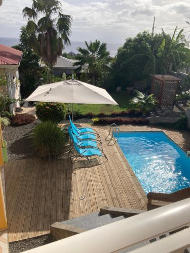 an umbrella and chairs next to a swimming pool at Bas de villa de 3 chambres et spa in Vieux-Habitants