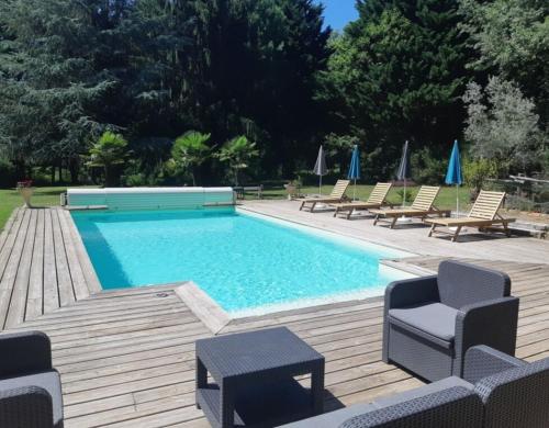a swimming pool with chairs and umbrellas at Maison de campagne - 5 chambres in Capdrot