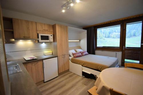 Cette petite chambre comprend un lit et une cuisine. dans l'établissement Résidence Le France - Studio Cabine 3/4 pers- LE FRANCE - PLAGNE CENTRE -pied des pistes MAE-9304, à Aime La Plagne