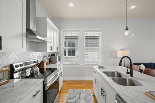 a white kitchen with a sink and a stove at NEW! Casa Fuente - Beautifully Renovated Ybor Bungalow, Steps to 7th Ave in Tampa