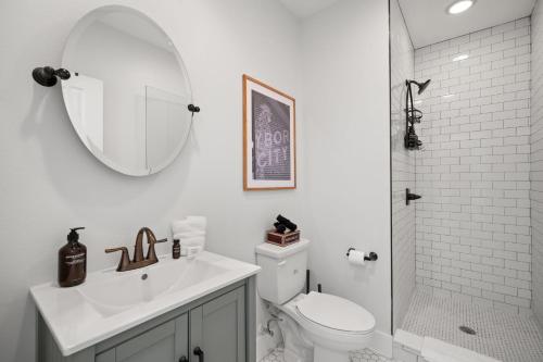 a bathroom with a sink and a toilet and a mirror at NEW! Casa Fuente - Beautifully Renovated Ybor Bungalow, Steps to 7th Ave in Tampa