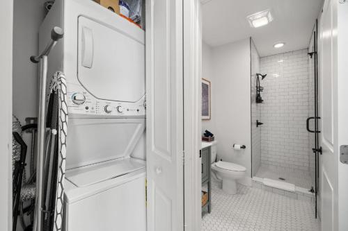 a white bathroom with a toilet and a shower at NEW! Casa Fuente - Beautifully Renovated Ybor Bungalow, Steps to 7th Ave in Tampa