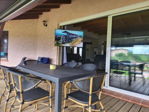 une table noire et des chaises sur un porche avec un écran dans l'établissement Villa aux portes des Pyrénées, à Saint-Gaudens